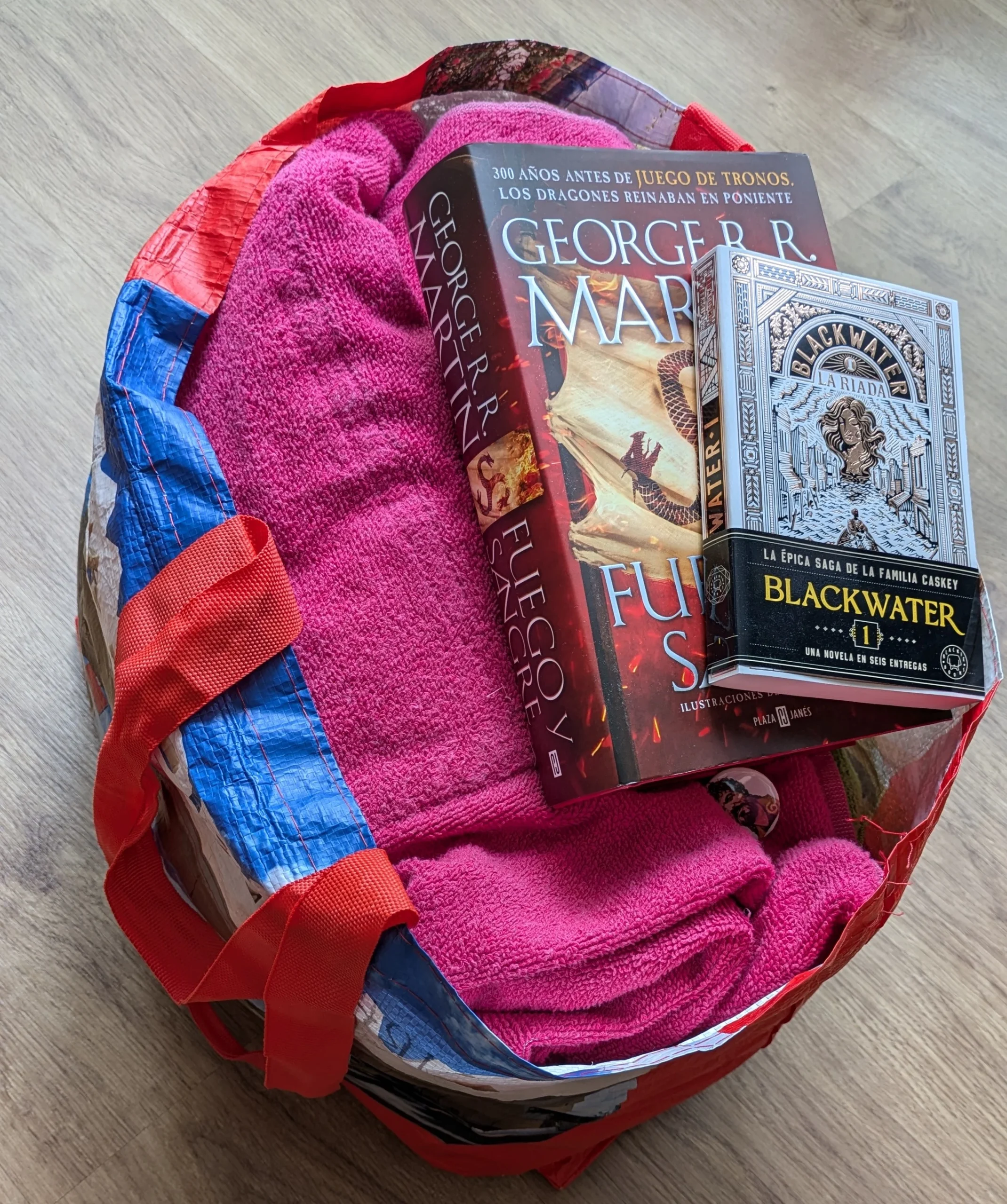 Una bolsa de toallas sobre las que están los libros Fuego y Sangre de George RR. Martin y el primer tomo de Blackwater. Se aprecia que el primero es mucho más estorbo que el segundo.
